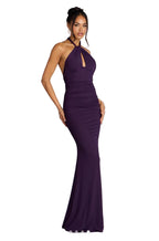 Woman wearing a purple halter neck gown on a gray background