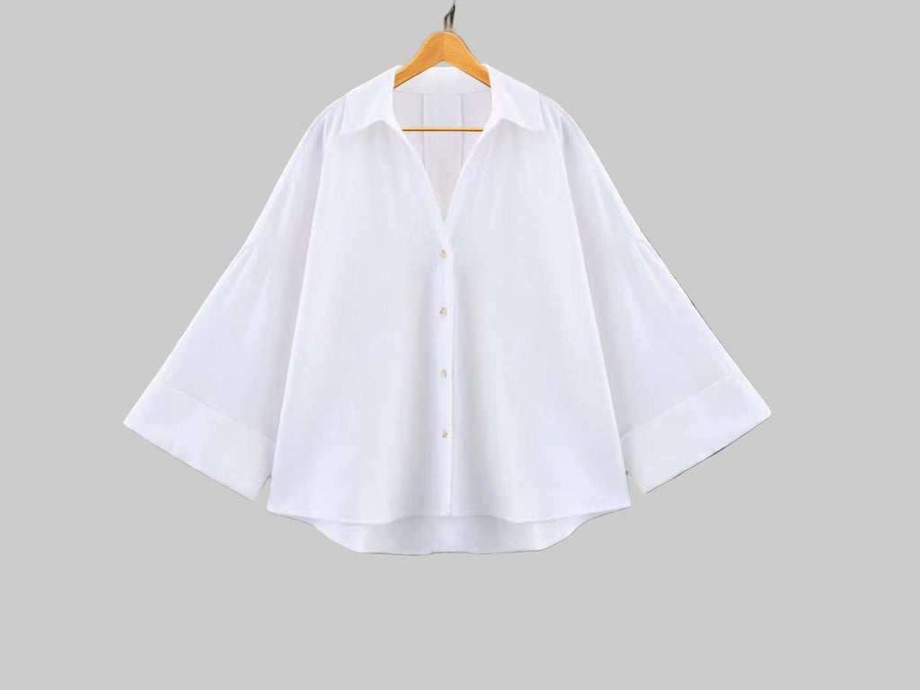 White shirt on a wooden hanger against a gray background
