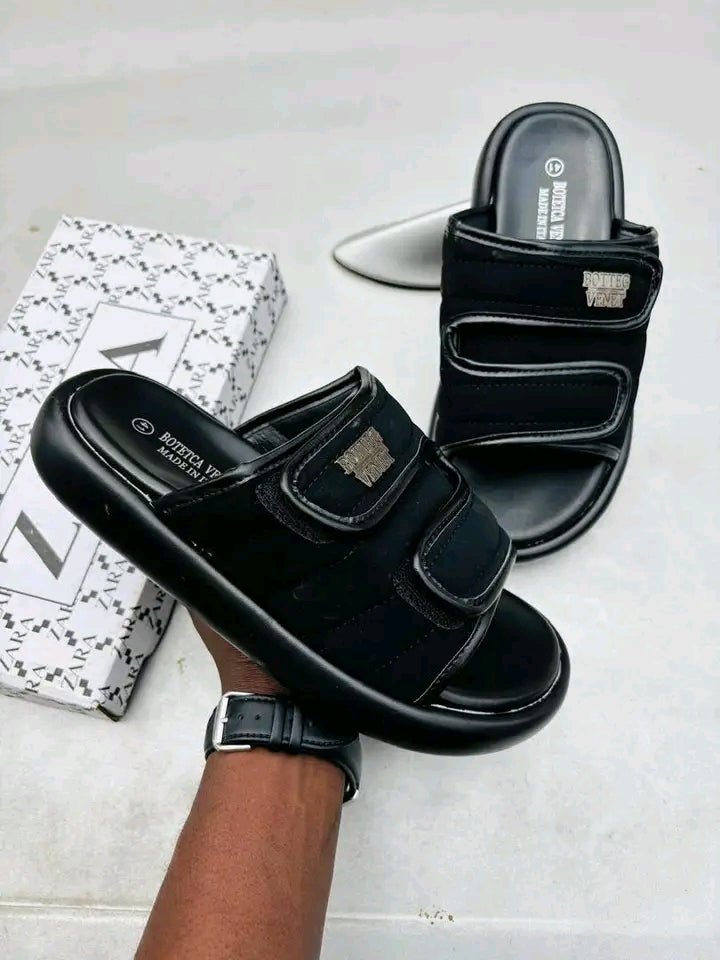 Black sandals with velcro straps on a light gray background