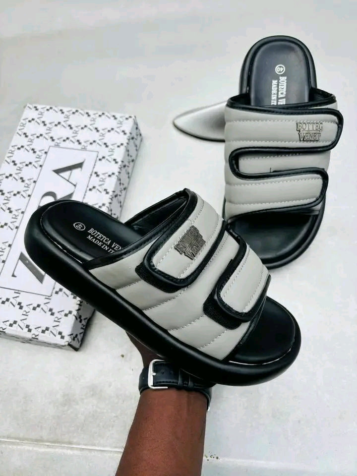 Gray and black sandals with a visible brand logo on a light gray surface.