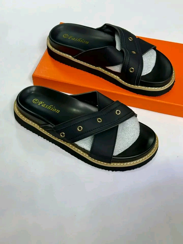 Black sandals with gold accents on an orange box against a white background