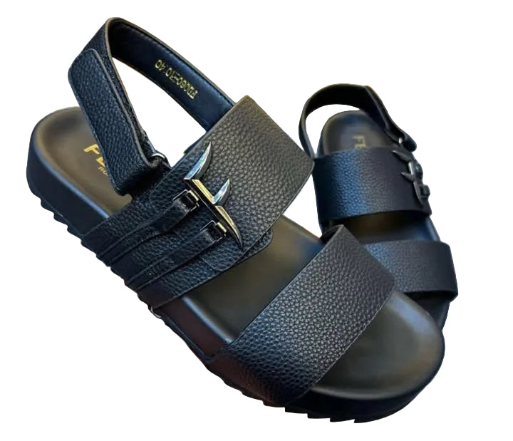 Black sandal with straps held by a hand on a gray surface